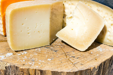 mix of various varieties of hard cheese on a wooden board.