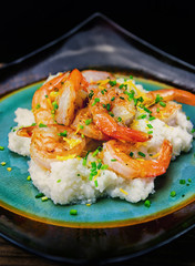Shrimp and grits on a square plate. Chive and cheese garnish. 