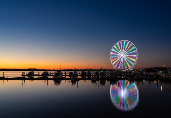 Illuminated ferris wheel at National Harbor near the nation capital of Washington DC at sunset - obrazy, fototapety, plakaty