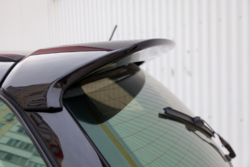 View of the trunk lid of a black car with a plastic spoiler over the rear window to improve the...