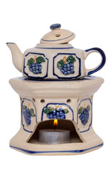 Closeup of a vintage teapot with warmer made of ceramic pottery with a colorful blue pattern isolated on a white background. The tea on the stove is kept warm with a tealight. Macro.