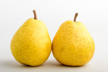 Two fresh organic ripe yellow pears on table, isolated on white background, side view with soft focus of tasty healthy food