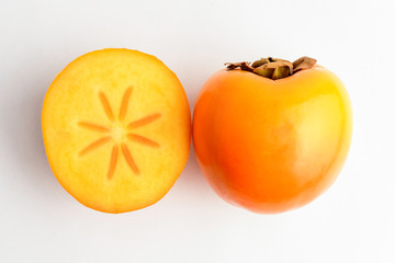 One fresh organic ripe orange kaki fruit on table and one half cut, isolated on white background, side view with soft focus of tasty healthy food
