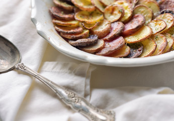 Thin sliced potatoes with crisp edges in a shallow baking dish. 