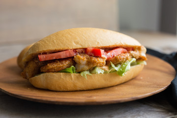 Shrimp po boy sandwich on a wooden plate. 