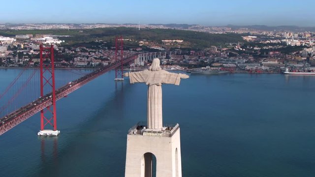 Aerial view of Lisbon cityscape showing Christ the King statue and 25 de Abril bridge over the Tagus river by day in Lisbon, Portugal.