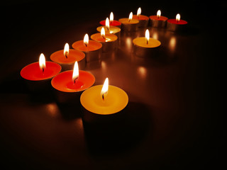Tealight candles with blurred dark background.