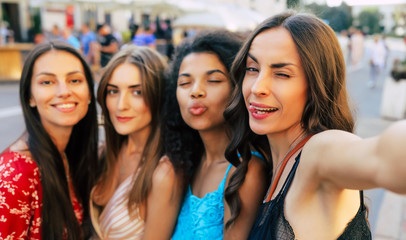 Instagram girls. A selfie photo of multicultural group of four smiley women, posing with various face expressions, which expose joy and contentment.