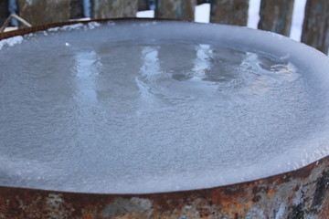  photo frozen water in a barrel.the tank is metal, rusty.is worth in the yard.time of year winter.around lies white snow.