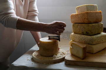 Scraping Device of Swiss Cheese Tete de moine. A man cuts cheese.