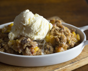 Homemade peach cobbler with a scoop of vanilla ice cream on top. 