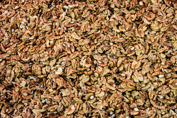 Heap of dried brown organic walnut kernels displayed for sale at a street food market, top view or flat lay of tasty healthy food photographed with soft focus