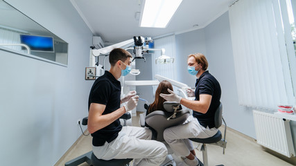 Two dentists examine the patient's teeth for the further treatment. Modern stomatology cabinet.