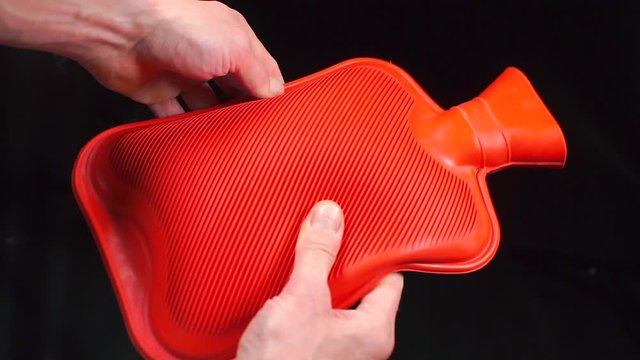 Red medical hot-water bottle in the doctors hands.