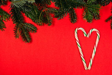 Weihnachten , ein Herz aus bunten Zuckerstangen , Tannenzweig , roter Hintergrund