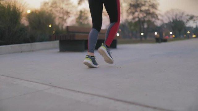 Young woman jogging in urban park at night time.