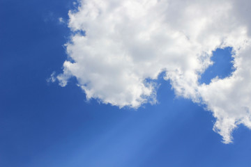 White cloud in the blue sky, faint ray of sun