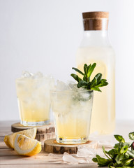 Lemon cocktail with mint in a glass on a light background.