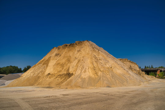 Sand slagheap for industrial needs. Blue sky background. Selective focus.