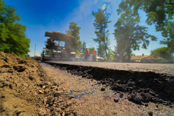 Road repair, compactor lays asphalt. Heavy special machines. Asphalt paver in operation. Side view. Closeup.