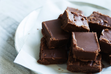 Close up of fudge, cut into single serving pieces on wax paper and light gray plate. 