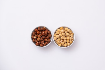 Raw and roasted hazelnuts on white background. Isolated hazelnuts in a bowl.