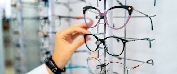 Row of glasses at an opticians. Eyeglasses shop. Stand with glasses in the store of optics. Woman's...