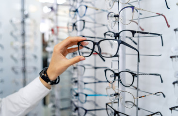 Row of glasses at an opticians. Eyeglasses shop. Stand with glasses in the store of optics. Woman...