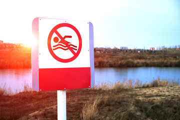 Sign bathing is prohibited on the background of an abandoned lake.At sunset.