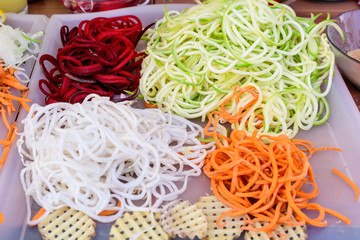 Fresh cut and grated organic vegetables ready for being cooked on a table, zucchini, potatoes, carrots, red onion and white cabbage photographed with selective focus