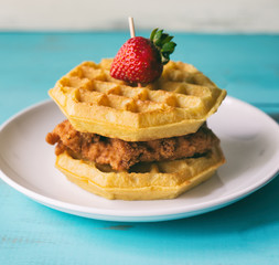 Fried chicken with waffles and a strawberry garnish. 