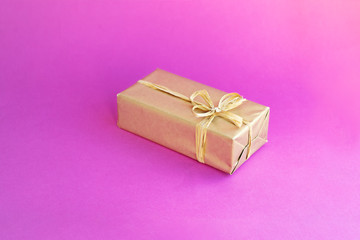 Golden box with a bow. Gift on a colored pink background. Great design for any purposes. Fashion, glamor background. New year, Christmas design.