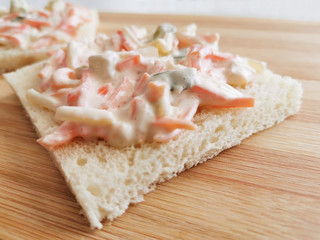 Coleslaw sandwich on a bamboo cutting board close up. 