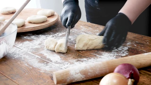 Fast food chef hands in gloves rolls out filo puff dough cuts roll, tart or cake on wooden board.