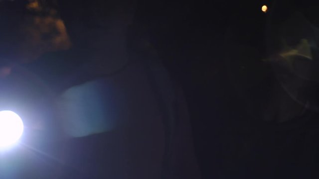 Young pair, man and woman with flashlight at night, turn it on and off, and go away, searching something. Dark background of night park.
