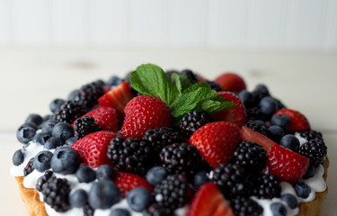 Close up view of a mixed berry pie with mint garnish. 