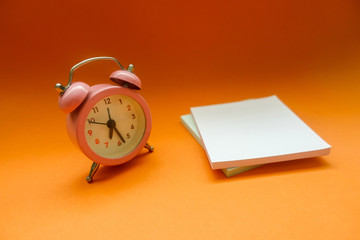 Alarm Clock And Adhesive Note Over Orange Background