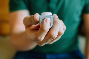 A young man is holding an asthma inhaler device while sitting on a couch