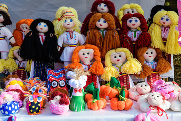 Fototapeta na wymiar Group of colourful textile hand made decorations, dolls and toys for children, available for sale at a traditional weekend market