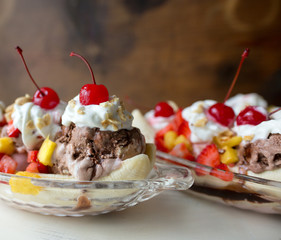 Two banana splits topped with whipped cream and cherries. 