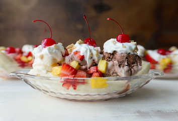 Banana split in a glass ice cream boat, made with fresh strawberries, pineapple, whipped cream and topped with maraschino cherries. 