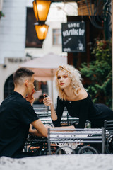 Sexy woman holds a lighter in her hand near her boyfriend sitting opposite with a cigarette in her hand.  The inscription on the plate 