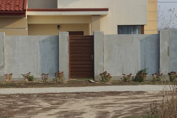 closed brown door and gray concrete fence on a rural street