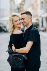 Fototapeta premium Stylish couple in black clothes hugging each other on city street