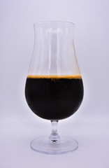 glass on white background, glass with dark beer, glass with dark liquid, filled glass goblet on leg