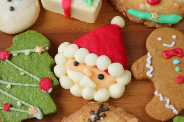 Fototapeta na wymiar Closeup of Colorful Santa and Many of Christmas Cookies on a Wooden Background