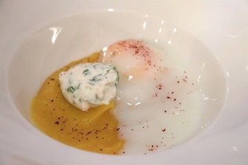 Oeuf mollet et crème de butternut dans une assiette blanche
