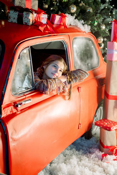 Two sisters in a christmas photo studio. Cute baby girl in a fashionable pin-up dress. many lights and garlands on the Christmas tree. Red retro car. Family celebration. Christmas holiday concept.
