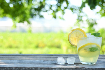 Glasses of lemon juice on a wooden table, summer set, outdoor greed blured background,boke.Water detox