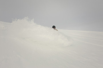 Paralympic snowboarder riding on the white hill in the snow cloud splash
